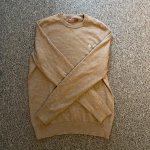 Beige merinoullströja från Morris - Säljer en stilren beige tröja från Morris i 100% merinoull. Tröjan har rund hals, ribbade muddar och en liten broderad logga på bröstet. Perfekt för dig som gillar klassisk och clean stil. Stl M men skulle säga att den sitter mer som S, passar dig som är 170-180! Mycket fint skick använd ett fåtal gånger👍 vid frågor eller funderingar är de bara att höra av sig!