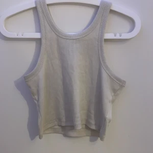 Ribbad vit linnetopp från 157 - Säljer en ribbad vit linnetopp från 157 i storlek S. Toppen har breda axelband och är croppad med en klassisk rund halsringning. Perfekt för varma dagar eller att styla lager på lager. Enkel och stilren design som funkar till mycket.