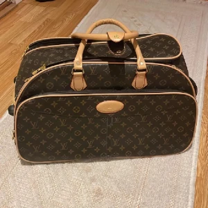  brun resväska med monogram ❤️NYSKICK❤️ - Säljer en lyxig resväska  klassiskt monogrammönster i brunt och beige. Väskan har två handtag, guldfärgade dragkedjor och detaljer i ljust skinn. Perfekt storlek för weekendresor och har flera fack för smart packning. Nyskick utan defekter alls och lyxig till resan. Ingen kvitto därav priset ❤️Använd gärna köp nu❤️