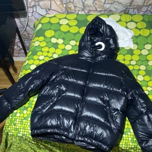 Moon blue  pufferjacka från Zara  - Säljer en moon blue  pufferjacka från Zara i storlek M. Jackan har en glansig finish, stora vadderade sektioner och en rejäl huva. Perfekt för kalla dagar när du vill hålla värmen och ändå se stilren ut. Stängs med dragkedja framtill pris kan diskuteras.