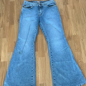Blå bootcut jeans från Zu Elements - Säljer ett par ljusblå jeans från Zu Elements med klassisk femficksdesign och tydlig bootcut-passform. Jeansen har normal midja och är tillverkade i jeansmaterial med snygg tvätt och slitningar. Perfekta för dig som gillar retrovibbar och breda ben.