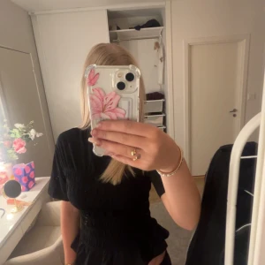 Svart blus med ribbat material💞 - Supersnygg blus från Gina tricot! Tröjan är ribbad från över brösten ner till volangen. Materialet är väldigt töjbart och har volang längst ner!