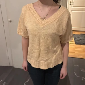 Beige stickad v-ringad topp - Superfin beige stickad topp med v-ringning och bred ribbad kant runt halsen. Toppen har korta ärmar med ribbade muddar och en avslappnad passform. Perfekt för dig som gillar en enkel men ändå snygg look. Använd gärna köp nu❤️
