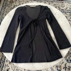 Svart omlottopp från Vila - Svart långärmad omlottopp från Vila med knyt framtill. Tunn och lätt transparent, perfekt för lager-på-lager. Djup v-ringning och smal passform som framhäver siluetten. Enkel men trendig design som funkar till många olika stilar. Använd gärna köp nu❤️