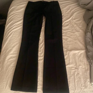 Svarta kostymbyxor med bootcut - Lågmidjade kostymbyxor från bikbok i modell Vera! Storlek 36 tall. Innerbenslängd ungefär 90cm och midjemått 36-39cm tvärs över står det på hemsidan. De har en liten tråd som sticker Rut men annars inga defekter