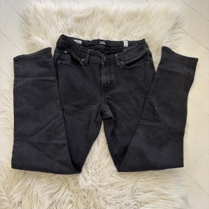 Svarta slim jeans Jack & Jones 158 - Svarta slim fit jeans från Jack & Jones i modellen Glenn. Klassisk femficksdesign, smal passform och normal midja. Jeansen är tillverkade i stretchig bomullsdenim för extra komfort och har snygga detaljer vid fickor och midja.