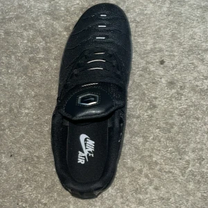 Svarta Nike Air Max sneakers - Säljer ett par svarta Nike Air Max sneakers med klassisk Air-dämpning i sulan. Skorna har mesh och syntetmaterial i ovandelen, snörning och diskret Nike-logga på sidan. Perfekta för dig som gillar en sportig och clean look.
