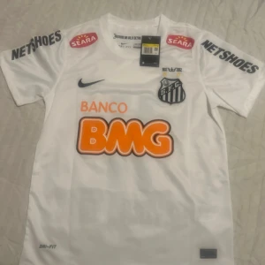 Santos Neymar Jr matchtröja Nike S - Vit Santos fotbollströja med Neymar Jr och nummer 11 på ryggen. Tröjan har korta ärmar, flera sponsorloggor och klubbmärke på bröstet. Tillverkad i Dri-FIT-material som andas. Klassisk passform och snygga svarta detaljer. Perfekt för fans av brasiliansk fotboll.