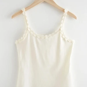 Vit linne med broderade blommor - Supersöt vit linnetopp med smala axelband och spetsblommor längs kanterna. Från Other&stories