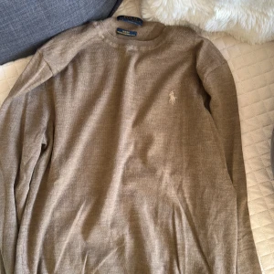 Beige långärmad tröja från Polo Ralph Lauren - Säljer en beige långärmad tröja från Polo Ralph Lauren med den klassiska broderade loggan på bröstet. Tröjan har rund hals och är tillverkad i mjuk bomull, perfekt för chill dagar. Enkel och stilren design som funkar till jeans eller chinos. Denna passar XS och S inte M. Den e aldrig använd aldrig. Den är slim fit. 