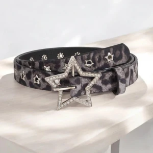 Leopardmönstrat bälte med stjärnspänne - Säljer ett snyggt bälte med leopardmönster i mörka och grå toner. Bältet har silverfärgade stjärn-nitar längs hela remmen och ett stort stjärnformat spänne dekorerat med glittriga stenar. Perfekt för att ge din outfit en cool och unik touch.