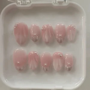 Rosa konstnaglar med pärldekor - Säljer ett set med konstnaglar i ljusrosa nyans med mjuk ombre-effekt. Naglarna har oval form och är dekorerade med små silverfärgade pärlor och stjärnor. Perfekt för dig som vill ha en söt och trendig look. Kommer i en vit förvaringsask.