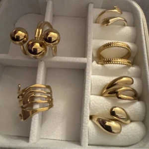 Set med sex  guldringar - Säljer ett set med sex trendiga chunky ringar i guldton. Ringarna har olika former: några med stora klot, andra med vågiga och droppformade detaljer samt en med pärlad kant. Perfekt för att mixa och matcha för en cool statement-look.