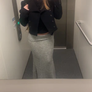 Grå ribbad långkjol stickad - Säljer en snygg grå stickad långkjol med ribbad struktur. Kjolen är figurnära och har en mjuk, stretchig känsla som gör den superbekväm. Perfekt att styla med en croppad jacka eller chunky sneakers för en cool look.