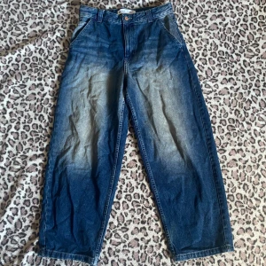 Blå baggy jeans  - Säljer ett par blå jeans från Bershka i modell med breda ben. Jeansen har klassisk femficksdesign, ljusare tvätt framtill och bak. Lite slitna längst ner.