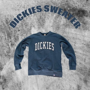 Blå sweatshirt från Dickies - Säljer en blå sweatshirt från Dickies med stort vitt broderat logotyptryck över bröstet. Tröjan har rund halsringning, ribbade muddar och är långärmad. Perfekt för dig som gillar streetwear och vill ha en klassisk look.