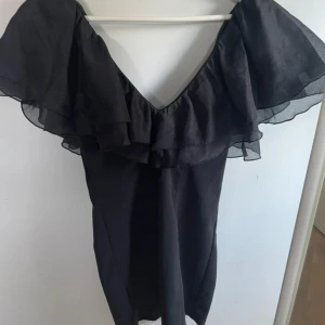 Svart volangklänning  - Svart klänning med volanger, tajt passform