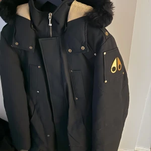 Svart dunjacka, Moose Knuckles - Svart dunjacka från Moose Knuckles med guldfärgade detaljer. Ordinarie pris 17000. Pris går att diskuteras vid snabb affär, använd fåtal gånger 