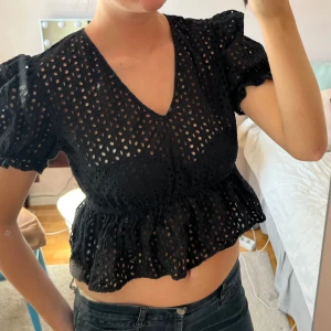 Svart blus med volang och hålmönster - Supersöt svart blus med v-ringning och korta puffärmar. Perfekt till en middag elelr festtopp💕 Finns ingen lapp men passar till en XS-M typ! Jag brukar oftast ha S i toppar och denna passar bra 
