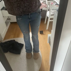 Lowwaist bootcut jeans  - Säljer ett par ljusblå bootcut jeans från gina tricot. Egengjorda slitna detaljer och hål vid knäna. Perfekt nu till hösten!! 