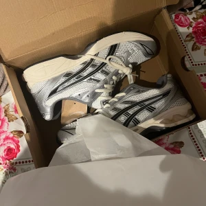 Silverfärgade sneakers från Asics - Säljer ett par snygga Asics sneakers i silver och vitt med svarta detaljer. 