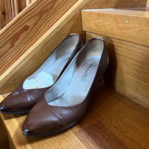 Bruna pumps med geometrisk detalj - Säljer ett par bruna pumps från Brunate med spetsig tå och klack. 