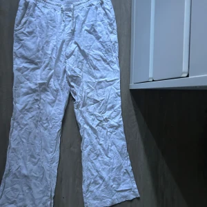 Vita linnebyxor från 157 - Säljer ett par vita linnebyxor från 157 med resår och snörning i midjan. Byxorna har raka ben och sidfickor, perfekta för varma dagar. Lätta och luftiga i materialet.