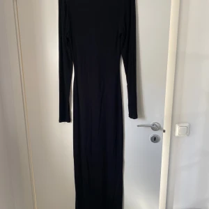 Svart långklänning med lång ärm - En svart, figurnära långklänning med långa ärmar och rundad halsringning. 