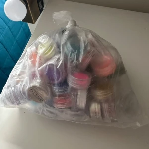  lösglitter i olika färger - Säljer ett stort gäng små burkar med lösglitter i olika färger, perfekt för smink eller naglar. Färgerna varierar från blått, rosa, lila till grönt och silver. Kommer i genomskinliga plastburkar med skruvlock.