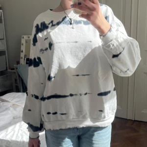 Vit och svart tie-dye sweatshirt - Säljer en oversized vit sweatshirt med svart tie-dye mönster från Levis. Tröjan har rund halsringning och långa ärmar. Perfekt för en avslappnad och trendig look.
