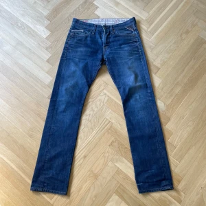 Blå Replay jeans straight fit - Säljer ett par klassiska blå jeans från Replay med raka ben och fem fickor. Jeansen har snygga slitningar och tydliga sömmar, samt Replay-lapp bak i midjan. Perfekta för dig som gillar en tidlös jeanslook.