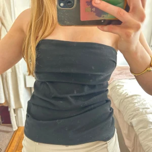 Svart tubtopp - Säljer en enkel svart tubtopp i mjukt bomullsmaterial. Toppen är ärmlös och har en tight passform som sitter snyggt på kroppen. Perfekt att matcha med jeans eller kjol för en stilren look.