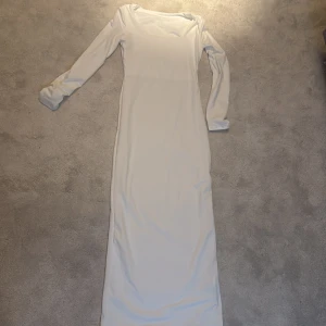 Vit långklänning med lång ärm - Säljer en elegant vit långklänning med lång ärm och rundad halsringning. Klänningen har en figurnära passform och är perfekt för speciella tillfällen. Aldrig använd, nytt skick, ställ frågor om de behövs 💕