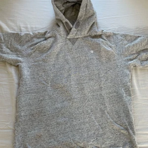 Grå hoodie från G-Star RAW - Säljer en ljusgrå hoodie från G-Star RAW med korta ärmar och klassisk huva. Tröjan har en enkel design med liten logga på bröstet. Skriv gärna för  fler bilder för funderingar kring hur den sitter 😀