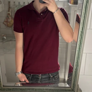 Vinröd pikétröja från Polo Ralph Lauren - vinröd pikétröja från Polo Ralph Lauren i nyskick. Köptes förra sommaren knappast använd nypris ca 1,5. Kom vid minsta fråga pris kan diskuteras vid snabb affär