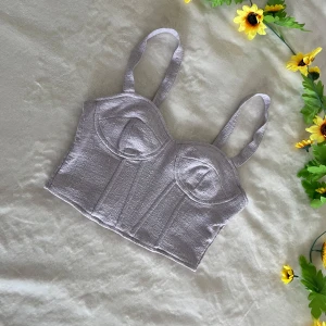 Ljuslila korsettopp med breda axelband - Trendig lila korsettopp med breda axelband och markerade sömmar framtill. Toppen har en croppad passform och är tillverkad i ett strukturerat tyg som ger en snygg look.