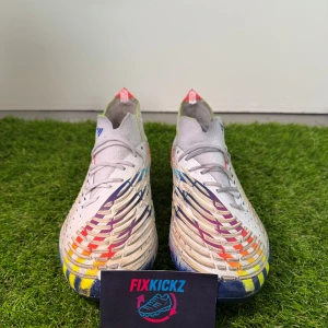 Adidas Predator fotbollsskor med färgglada detaljer - Adidas Predator Edge.1 FG “Al Rihla” – Football Boots  Selling a pair of Adidas Predator Edge.1 FG from the limited Al Rihla Pack. 	•	Size: 41 + 1/2 	•	Condition:Gently Used 	•	Technology: 	•	Zone Skin upper for enhanced ball control with strategically placed rubber elements. 	•	FacetFrame outsole for maximum traction and stability during quick movements.                   Retail Price 280€