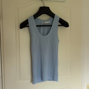 Ljusblå ribbad linnetopp från Zara - Säljer en ljusblå ribbad linnetopp från Zara. Toppen är ärmlös med rund halsringning och har en tight passform. Perfekt för varma dagar eller som layering-plagg.