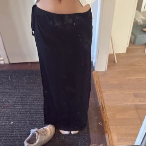 Svart långkjol från BikBok - Säljer en svart långkjol från BikBok i storlek XS. Kjolen har en enkel och stilren design med knytning i midjan och är tillverkad i ett mjukt, stretchigt material. Perfekt för dig som gillar en klassisk look.