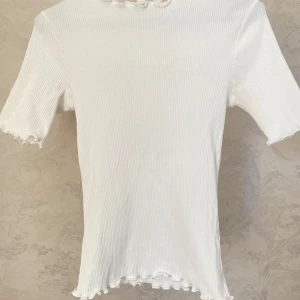 Vit ribbad topp från NA-KD - Säljer en vit ribbad topp från NA-KD i stretchigt material. Använd ett fåtal gånger.