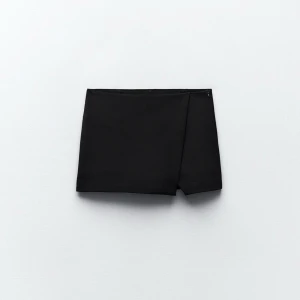 Svart kortkjol med omlott - Snygg svart kortkjol med omlott från Zara, det är modellen som är kjol hela vägen alltså inte shorts baktill! Använd 1 gång , säljer då den inte passade. Säljs inte på Zara längre, köpt förra sommaren 🫶 