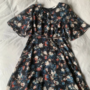 Blommig klänning  - Säljer denna somriga klänning luftiga ärmar och fint fall. Möjligt att knyta runt midjan. Bara genomskinlig vid ärmarna! 🌸🌸