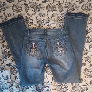 Blå bootcut jeans med broderade bakfickor - Säljer ett par blå bootcut jeans med snygga broderade detaljer på bakfickorna. Köpta på vinted.