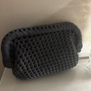 Grå handvirkad väska/clutch! - Säljer en grå handvirkad clutch / handväska som jag har virkat!. Väskan är i ett mjukt garn och är väldigt rymlig! Kan bäras i handen som en clutch eller bäras i handtaget.  Kan Även Göra Andra Färger / storlekar💕 skriv för mått, olika på vissa 💕