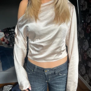 Champagnefärgad oneshoulder-top i satin - Säljer en champagnefärgad oneshoulder-top i glansigt satinmaterial. Skriv för fler bilder eller frågor!!