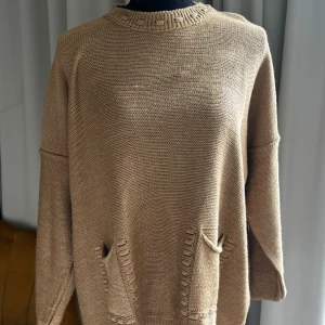 Beige stickad tröja med fickor - Säljer en beige stickad tröja med två snygga fickor framtill. Tröjan har rund halsringning med ribbad kant och långa ärmar. Perfekt för våren och enkel att matcha med olika outfits.