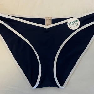 Mörkblå bikiniunderdel med vita kanter - Snygg mörkblå bikiniunderdel med kontrasterande vita kanter. Tyvärr för små för mig. Aldrig använda. 