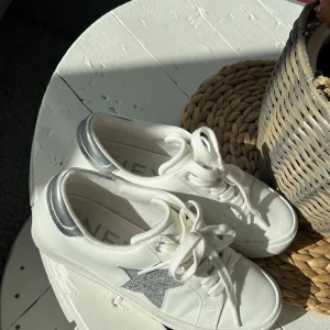 Vita NEXT sneakers med silvrig glitter stjärna - Snygga vita sneakers med en glittrig silverstjärna på sidan och matchande silverdetaljer vid hälen. Endast undersidan är oren. Skorna är i storlek 38 men passar även 37💞 