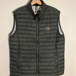 Mörkgrön dunväst från Colmar - Snygg och praktisk grön dunväst från Colmar med dragkedja framtill och två fickor med dragkedjor. Perfekt nu till lite varmare väder och kan användas med tröja under och även t shirt. Passar till vardags och mer uppklätt. Skick 8/10. Nypris: 2899, Mitt pris: 799. Vid intresse skicka gärna ett meddelande!