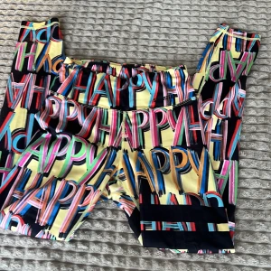 Stronger byxor - Säljer ett par färgglada stronger byxor med texten 'HAPPY' i olika färger. Träningsbyxornahar en elastisk midja och är perfekta för en glad och lekfull stil. De är gjorda i ett mjukt och bekvämt material.